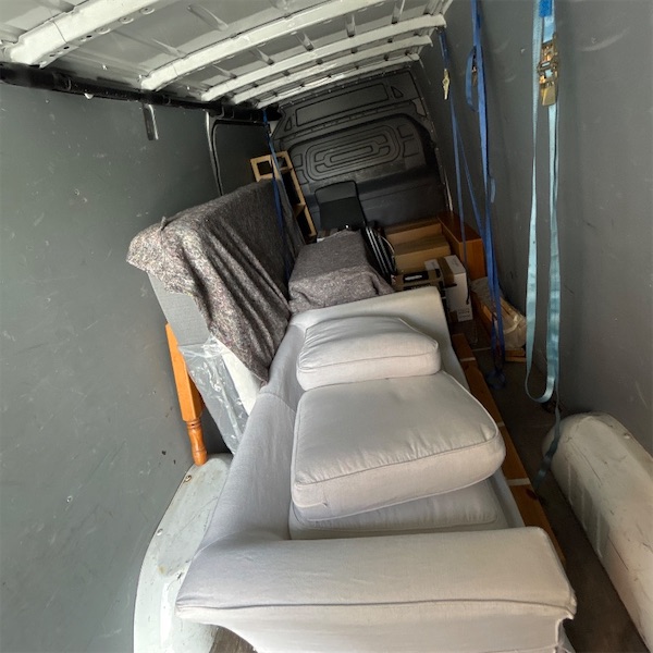 A two-seater sofa strapped to the side wall of a long van