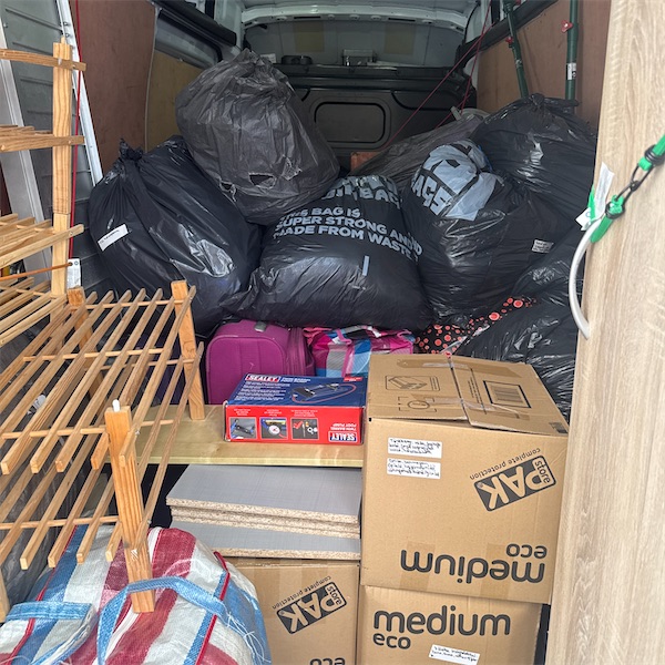 A van loaded to the roof with bags, boxes and a shoe rack